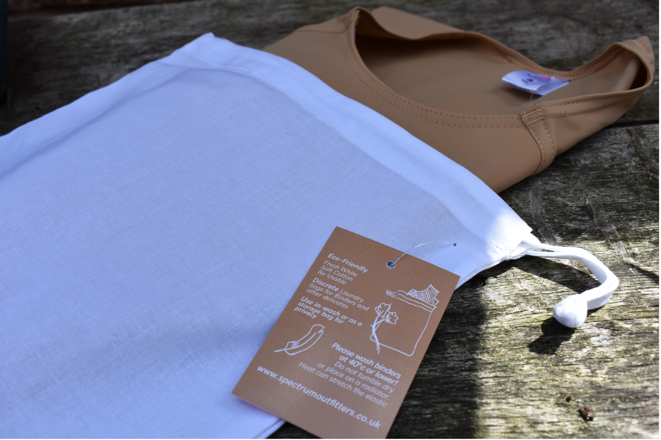 Brown chest binder in a with a white laundry bag on a wooden surface