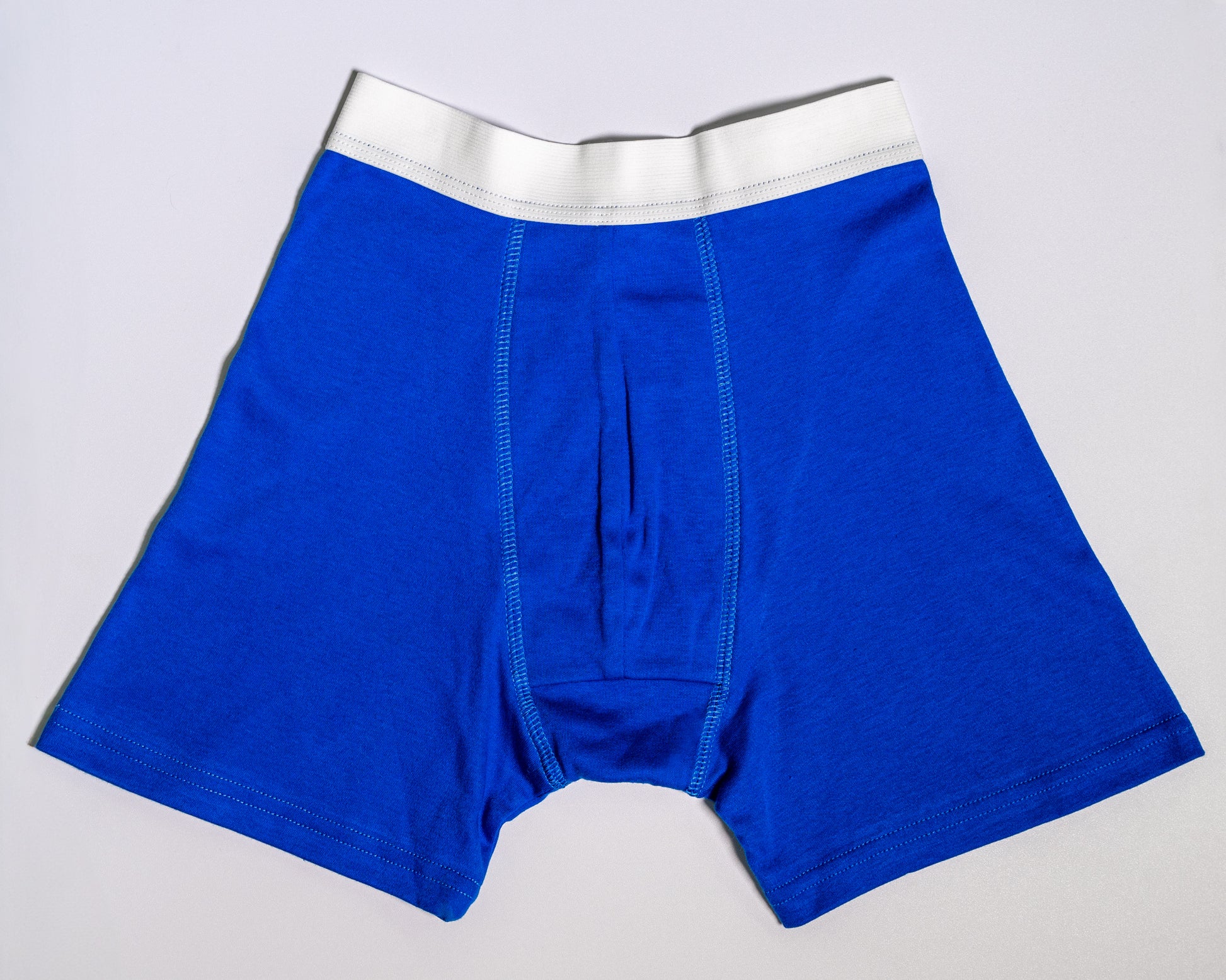 Blue boxer briefs with a white waistband on a light gray background