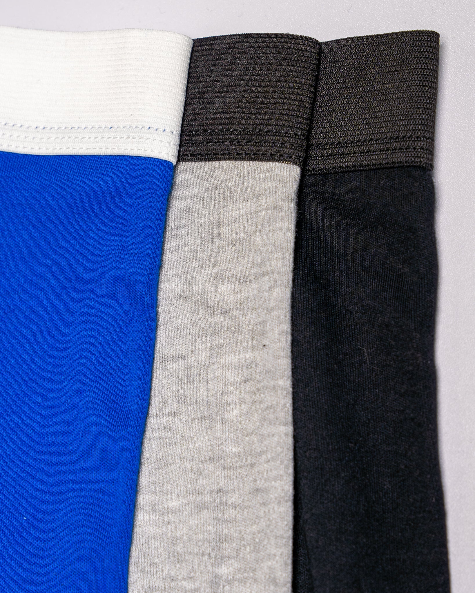 Three pairs of boxers in blue, gray, and black on a white background