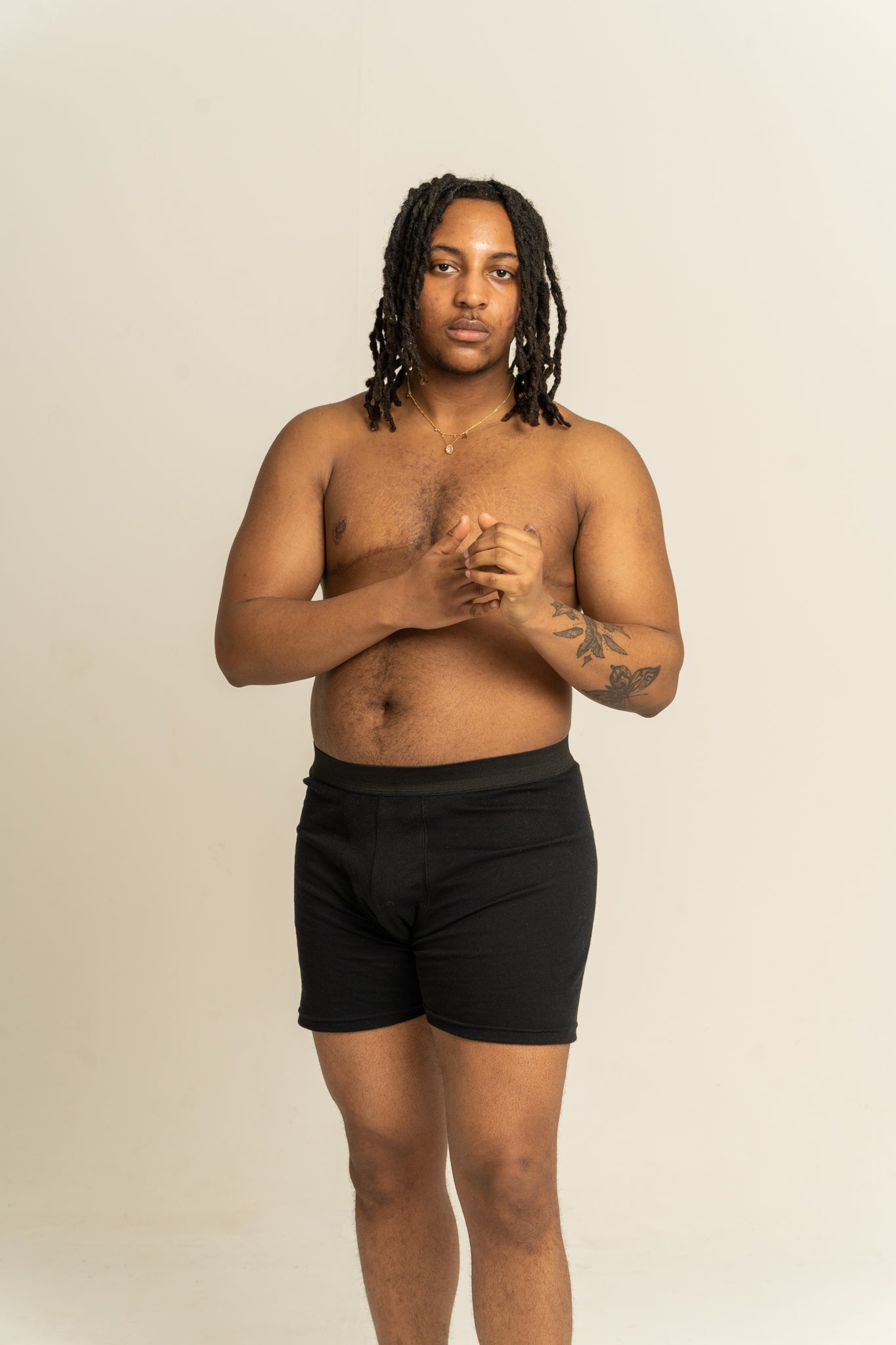 Man wearing black boxer briefs against a beige background