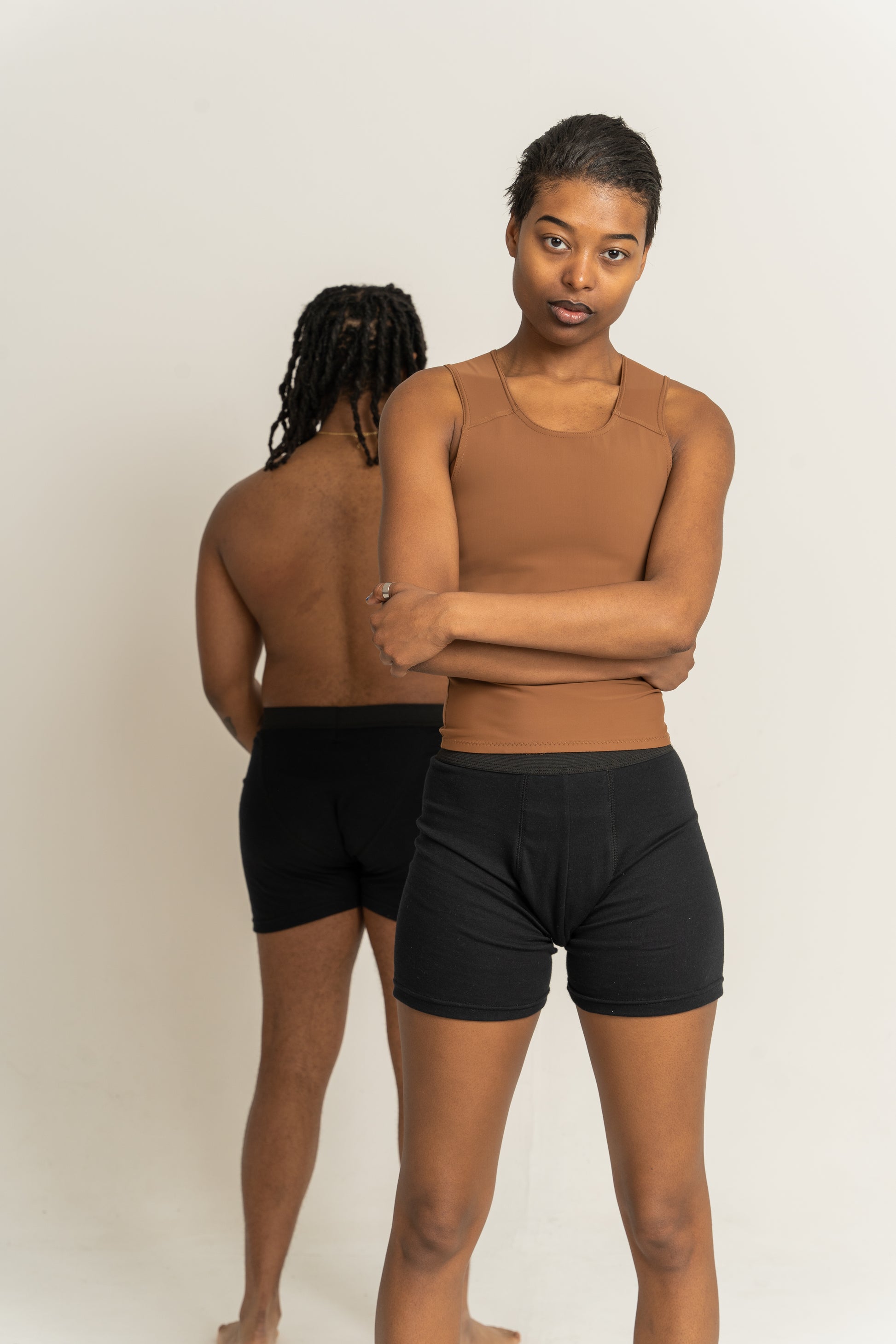 Two people wearing black boxers against a plain background